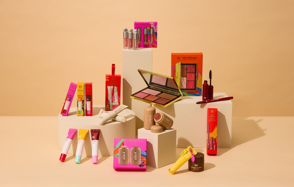 A variety of colourful makeup products displayed on white pedestals, featuring lipsticks, palettes, and skincare against a beige background.