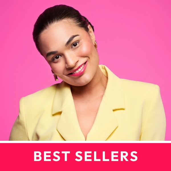 Smiling woman in a yellow blazer with elegant earrings, on a pink background. Text reads, "BEST SELLERS."