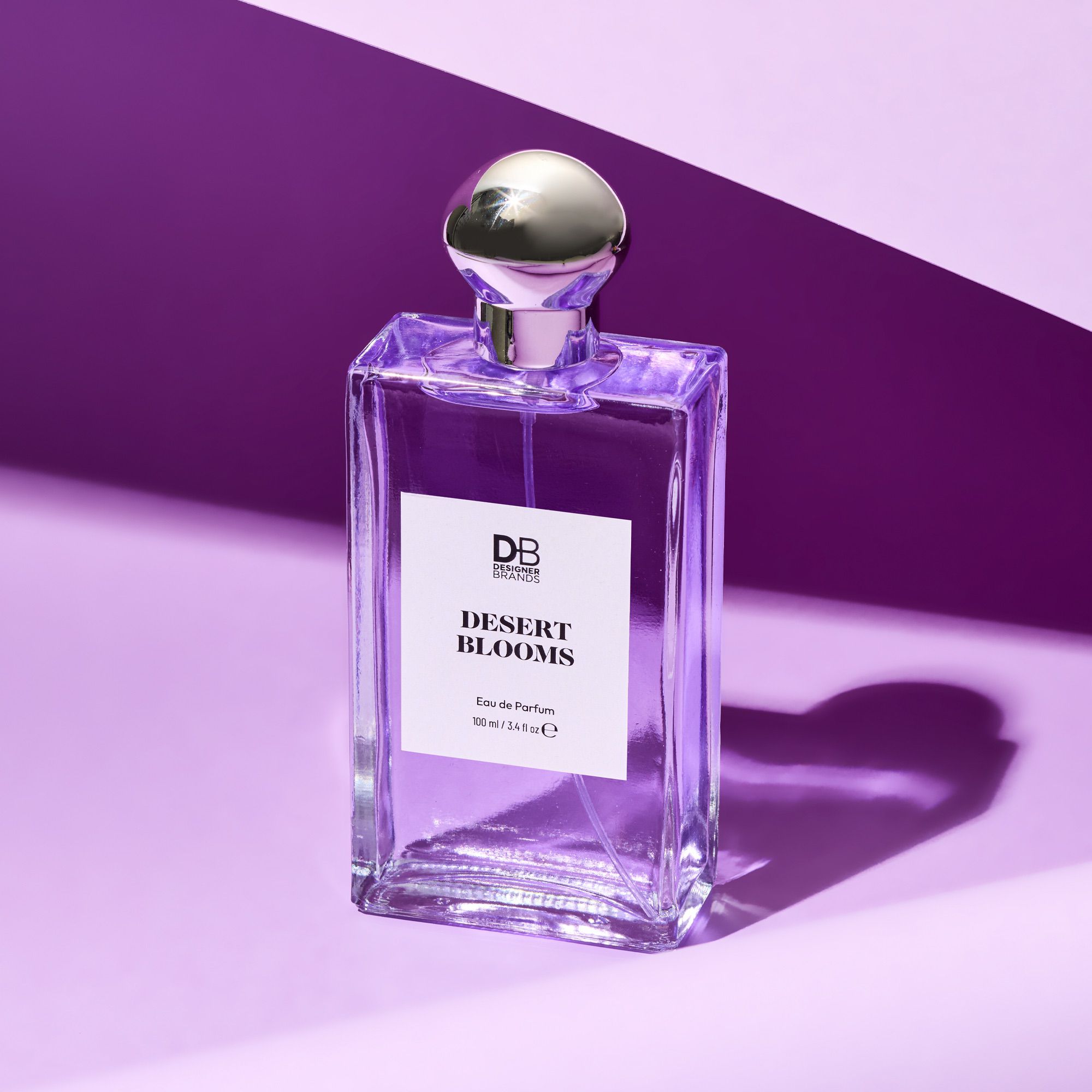 Perfume bottle labeled 'Desert Blooms' with a silver cap on a purple background
