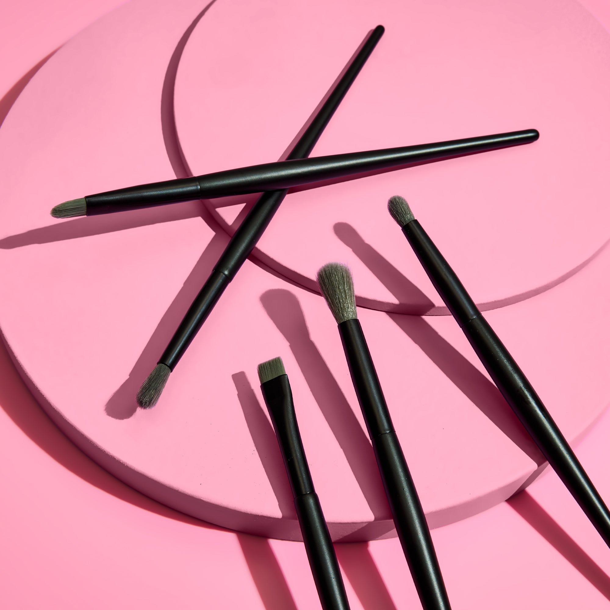 Makeup brushes on a pink background
