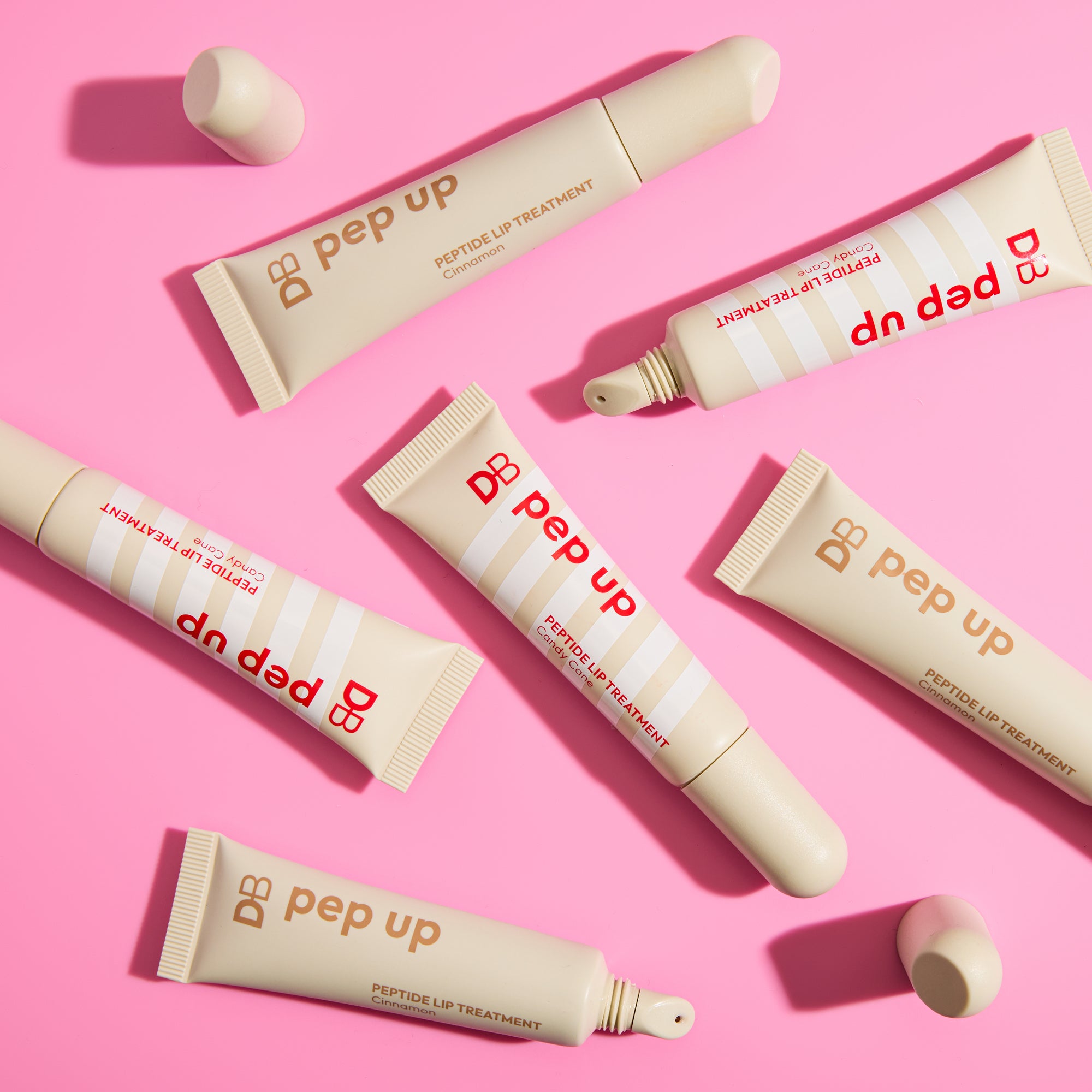DB Pep Up peptide lip treatment tubes on a pink background